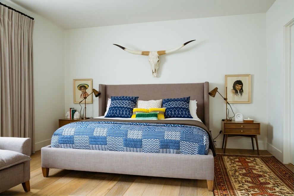 カルガリーにある広いカントリー風のおしゃれな客用寝室 (白い壁、淡色無垢フローリング、ベージュの床)