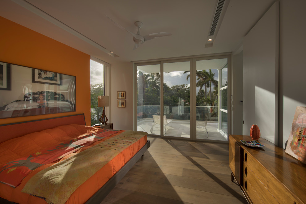 Modelo de dormitorio tipo loft minimalista grande con parades naranjas, suelo de madera clara y suelo marrón
