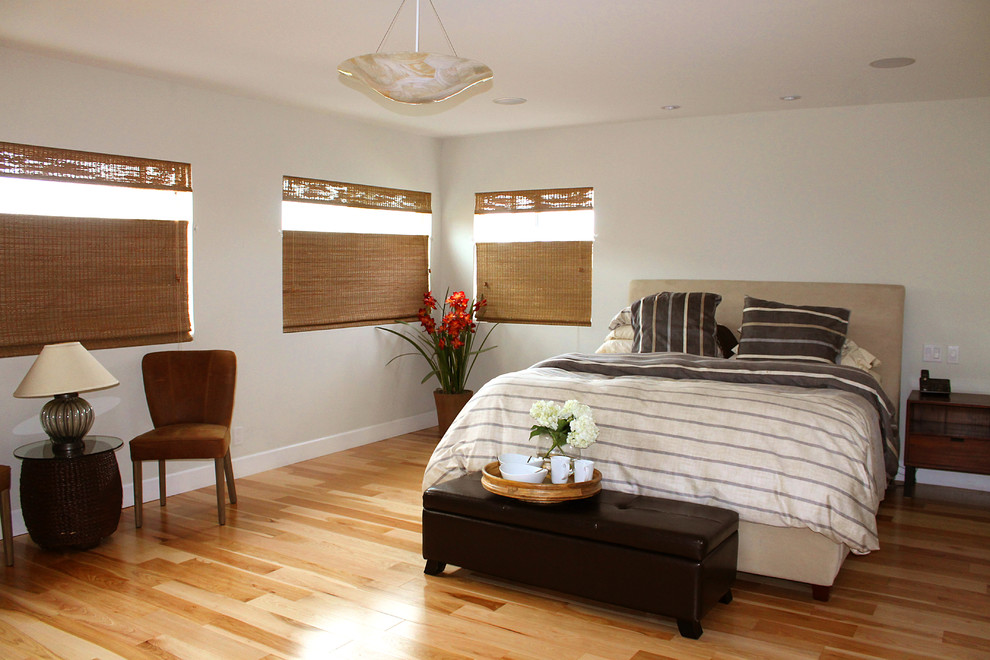 Modelo de dormitorio principal y blanco actual grande sin chimenea con paredes grises y suelo de madera clara