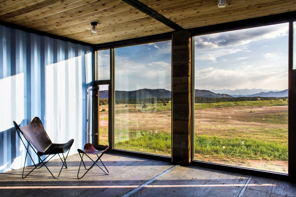 Kleines Industrial Gästezimmer ohne Kamin mit blauer Wandfarbe und Sperrholzboden in Denver