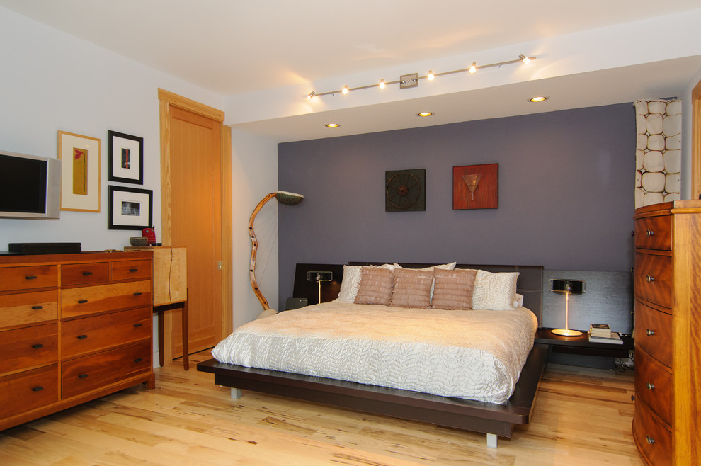 Immagine di una camera da letto design con pareti grigie e pavimento in legno massello medio