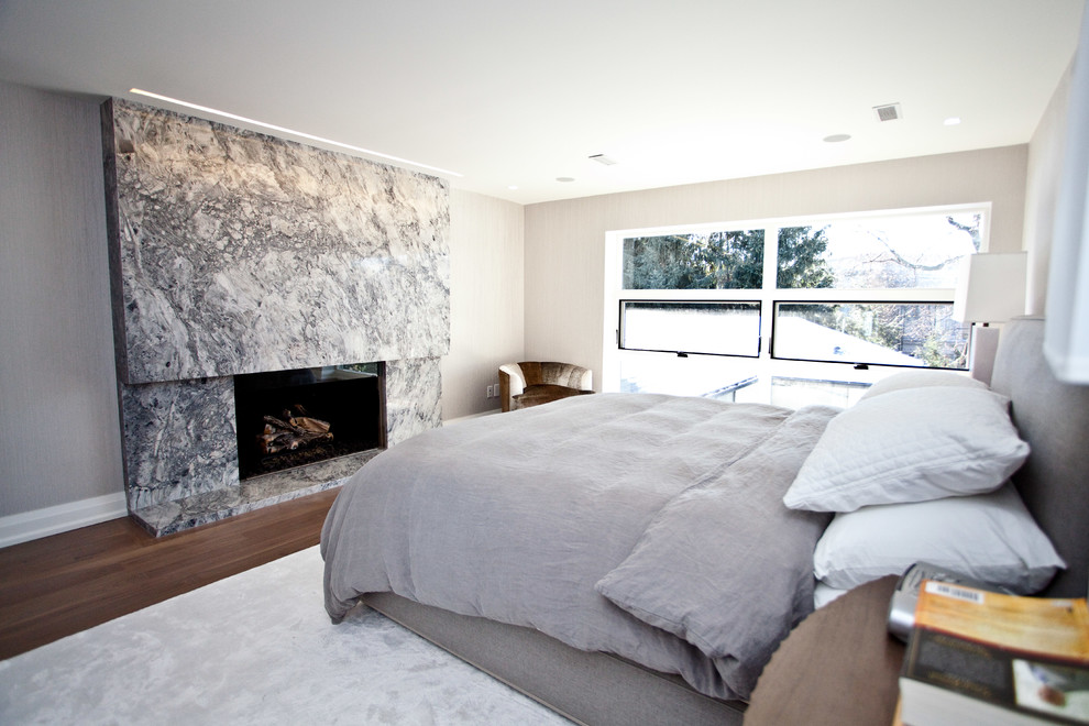 Diseño de dormitorio contemporáneo con paredes beige, suelo de madera oscura, todas las chimeneas y marco de chimenea de piedra