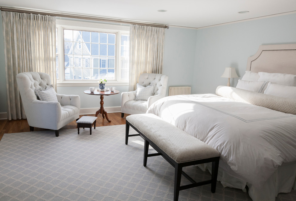 Modelo de dormitorio principal tradicional de tamaño medio sin chimenea con paredes azules y suelo de madera en tonos medios