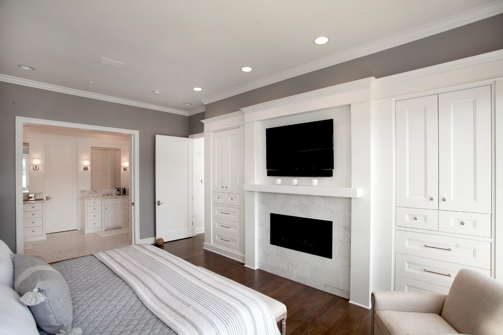 Imagen de dormitorio principal tradicional con paredes grises, suelo de madera oscura, chimenea lineal, marco de chimenea de baldosas y/o azulejos y suelo marrón
