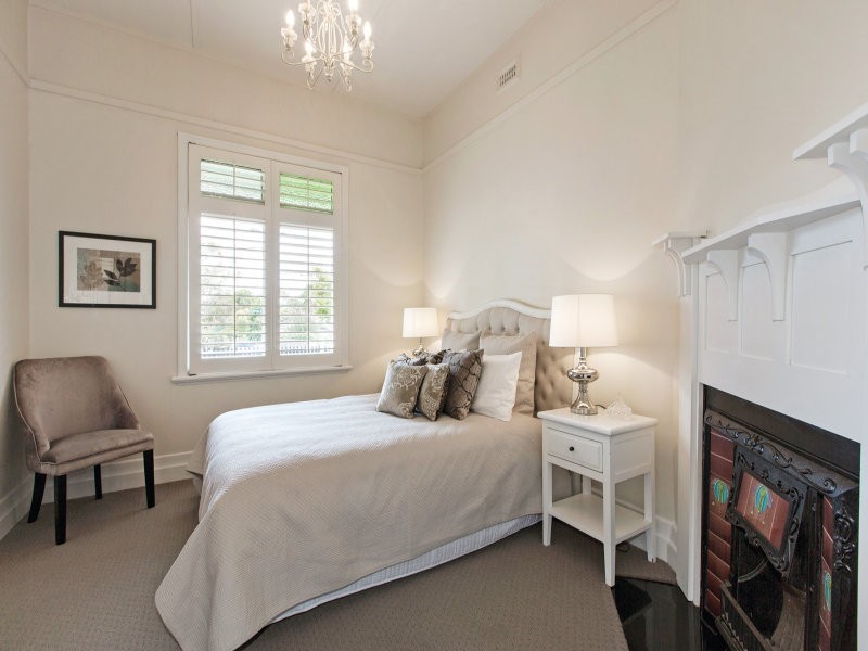 Inspiration pour une chambre minimaliste avec un mur blanc, une cheminée d'angle, un manteau de cheminée en bois et un sol marron.