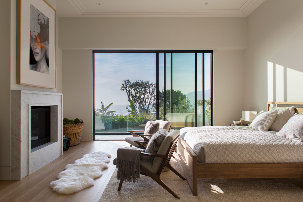 Идея дизайна: спальня в современном стиле с серыми стенами, паркетным полом среднего тона и стандартным камином