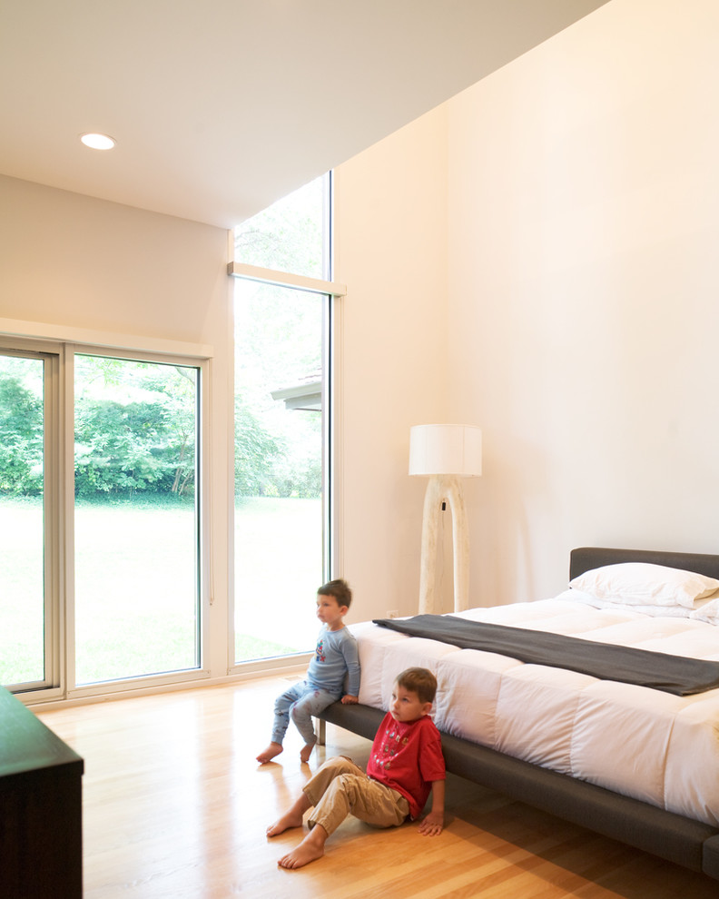 На фото: спальня на мансарде в стиле модернизм с белыми стенами и паркетным полом среднего тона