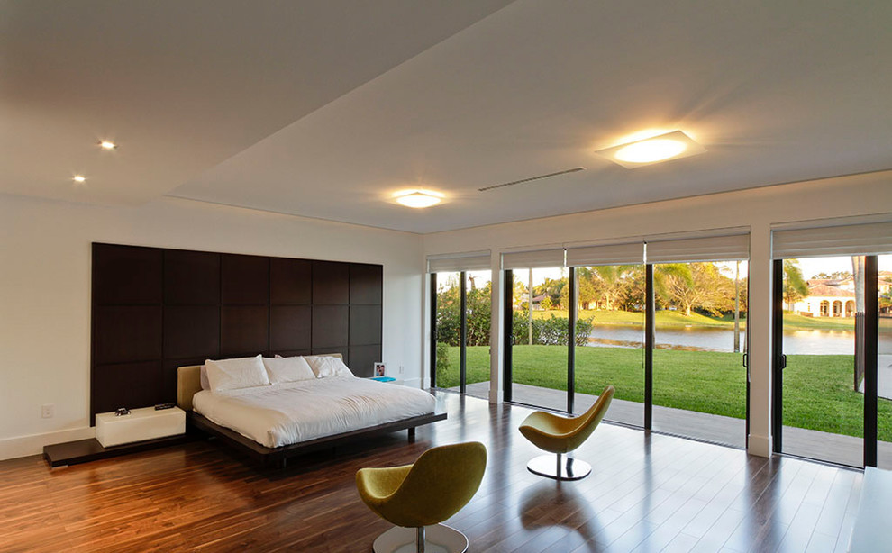 Immagine di una grande camera matrimoniale moderna con pareti bianche, pavimento in bambù e pavimento marrone