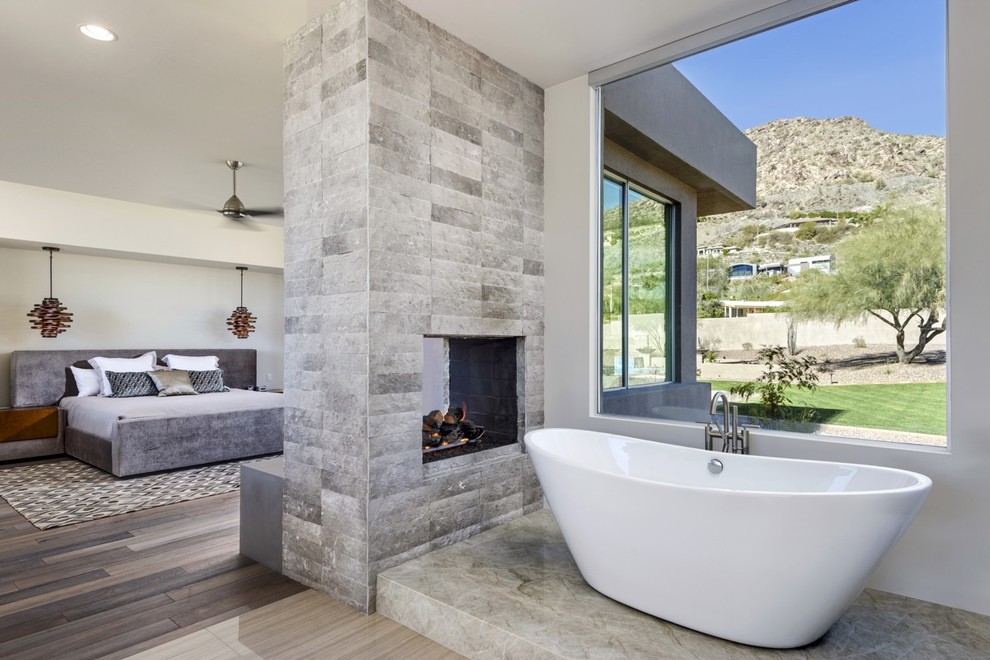 Inspiration for a large modern master dark wood floor bedroom remodel in Phoenix with white walls, a two-sided fireplace and a stone fireplace