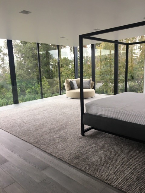 Foto de dormitorio principal minimalista extra grande con paredes grises, suelo de madera en tonos medios y suelo gris