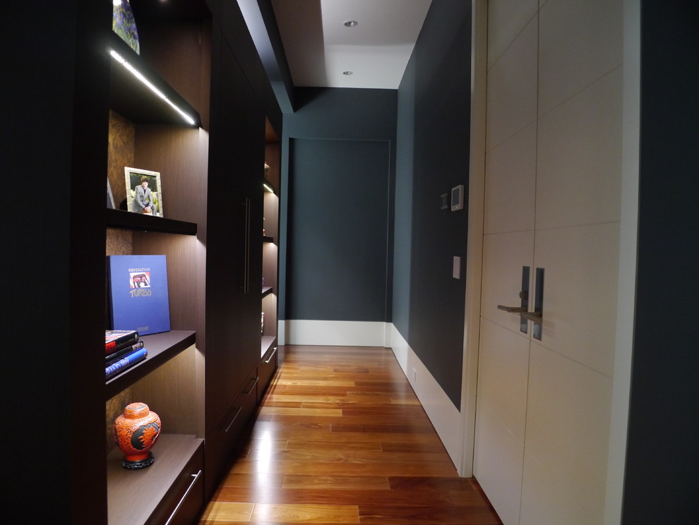 Cette photo montre une grande chambre parentale moderne avec un mur noir et un sol en bois brun.