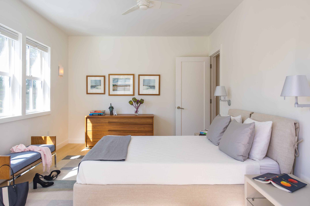 Trendy medium tone wood floor and brown floor bedroom photo in Boston with white walls