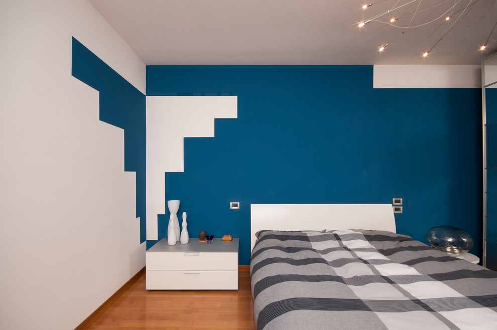 Idéer för ett modernt huvudsovrum, med blå väggar och mellanmörkt trägolv