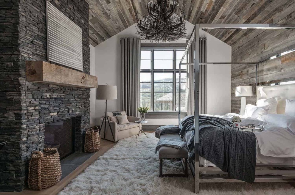 Uriges Hauptschlafzimmer mit weißer Wandfarbe, hellem Holzboden, Kamin und Kaminumrandung aus Stein in Denver