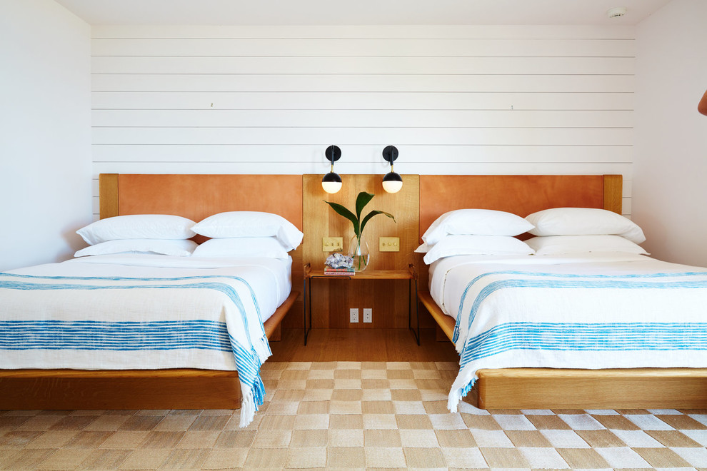 Cette image montre une chambre d'amis marine avec un mur blanc, un sol en bois brun et un sol marron.