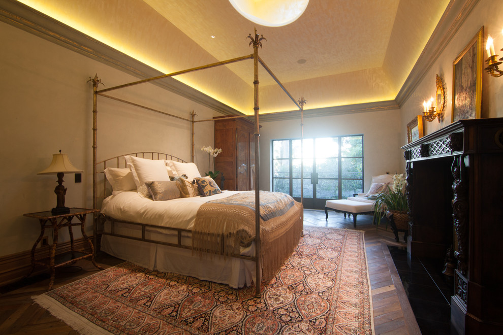Aménagement d'une grande chambre parentale classique avec un mur beige, parquet foncé, une cheminée standard, un manteau de cheminée en bois et un sol marron.