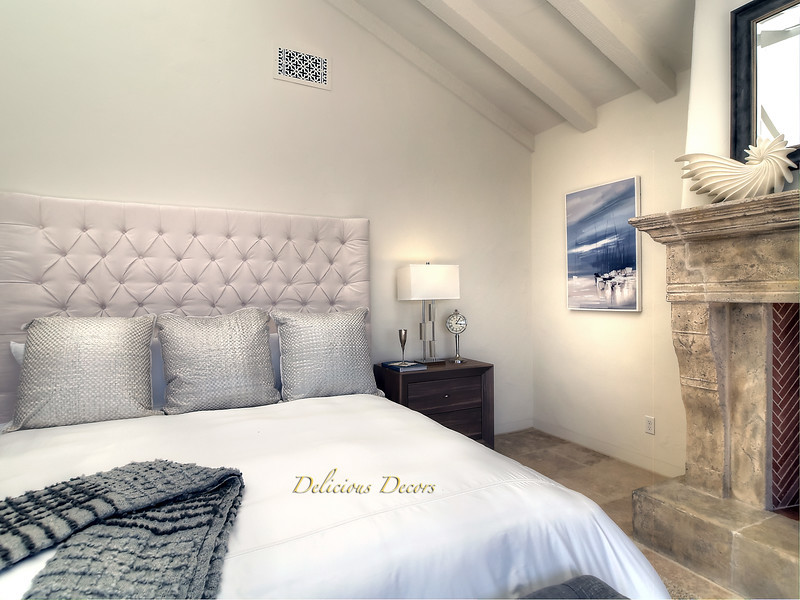 This is an example of a mediterranean master bedroom in Santa Barbara with beige walls, ceramic flooring, a standard fireplace and beige floors.