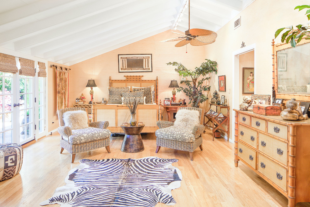 Large world-inspired master bedroom in Santa Barbara with beige walls and light hardwood flooring.