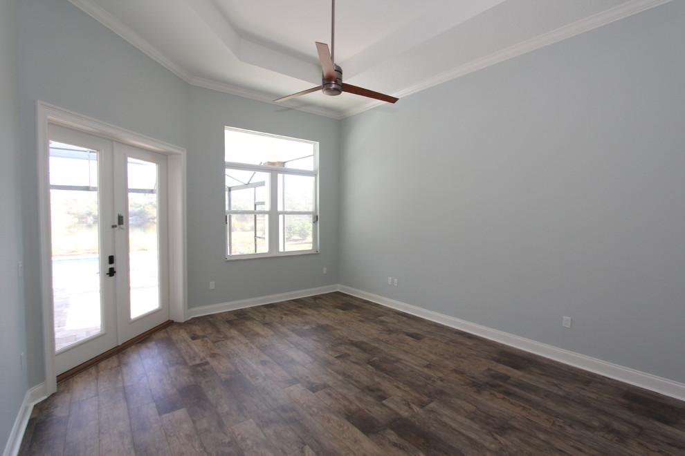 Large mediterranean master bedroom in Orlando with grey walls, laminate floors and brown floors.
