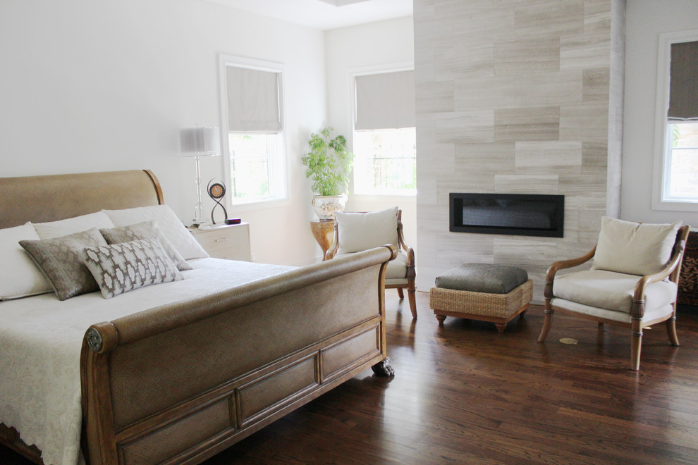 Großes Modernes Hauptschlafzimmer mit weißer Wandfarbe, dunklem Holzboden, Gaskamin, gefliester Kaminumrandung und braunem Boden in Dallas