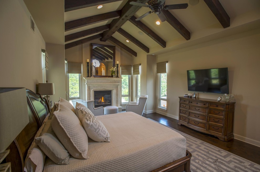 Cette photo montre une chambre parentale tendance de taille moyenne avec un sol en bois brun, une cheminée standard et un manteau de cheminée en pierre.