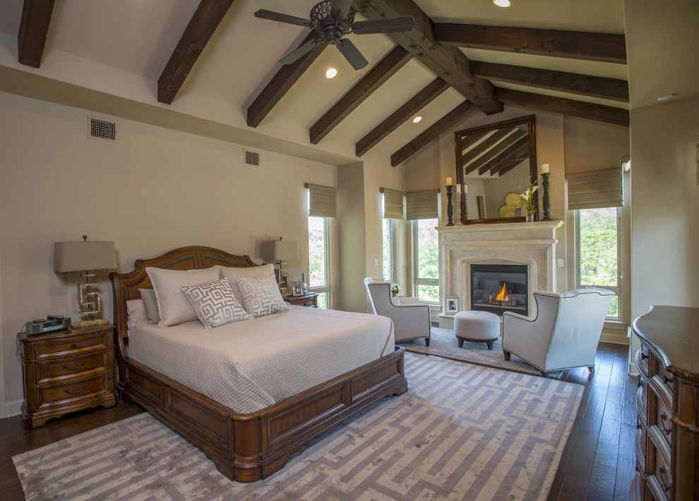 Photo of a large traditional master and grey and brown bedroom in Austin with medium hardwood flooring, beige walls, a standard fireplace and brown floors.