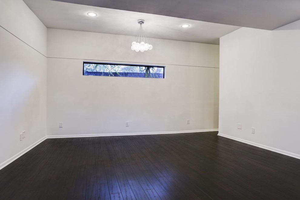Bild på ett stort funkis gästrum, med vita väggar och mörkt trägolv