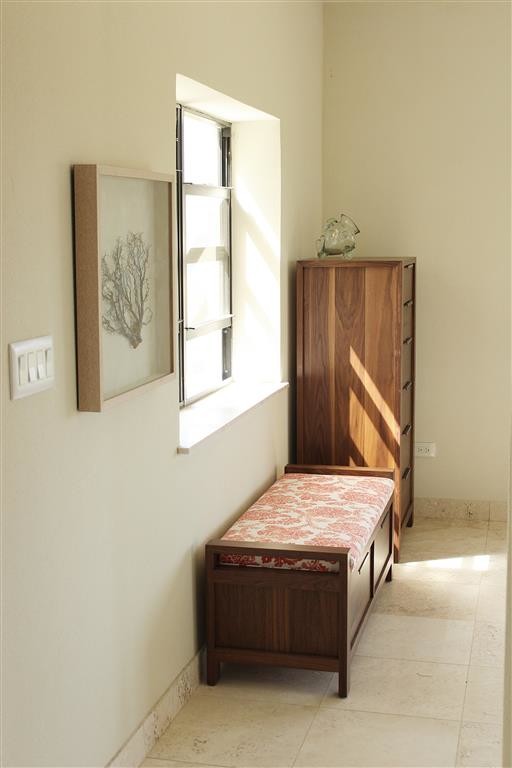 Modelo de habitación de invitados costera de tamaño medio con paredes beige y suelo de travertino