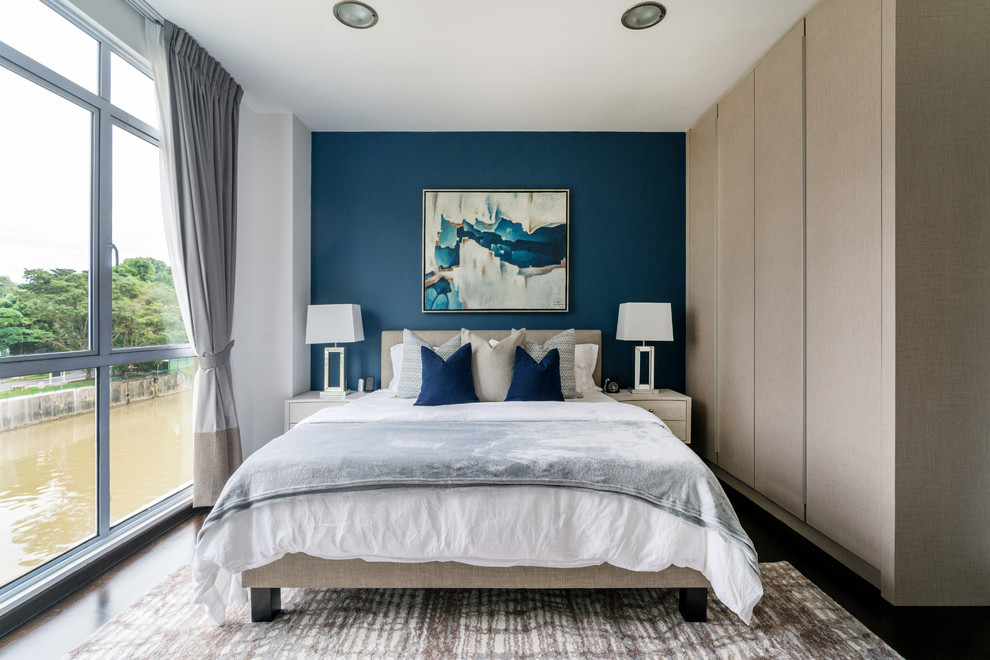 Foto di una camera da letto design con pareti blu, parquet scuro e pavimento marrone