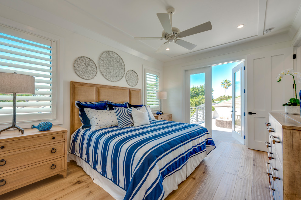 Example of a large beach style guest light wood floor and brown floor bedroom design in Miami with white walls and no fireplace
