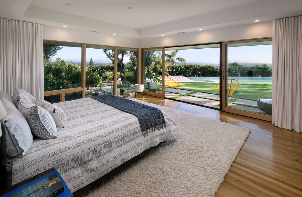 Retro Schlafzimmer mit weißer Wandfarbe, braunem Holzboden und braunem Boden in Santa Barbara