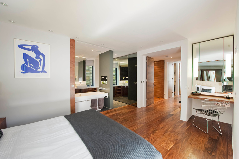 Modelo de dormitorio principal moderno sin chimenea con paredes blancas y suelo de madera en tonos medios