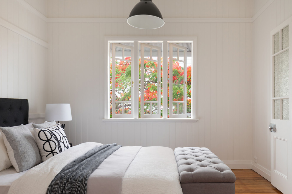 Diseño de dormitorio marinero con paredes blancas, suelo de madera en tonos medios y suelo marrón