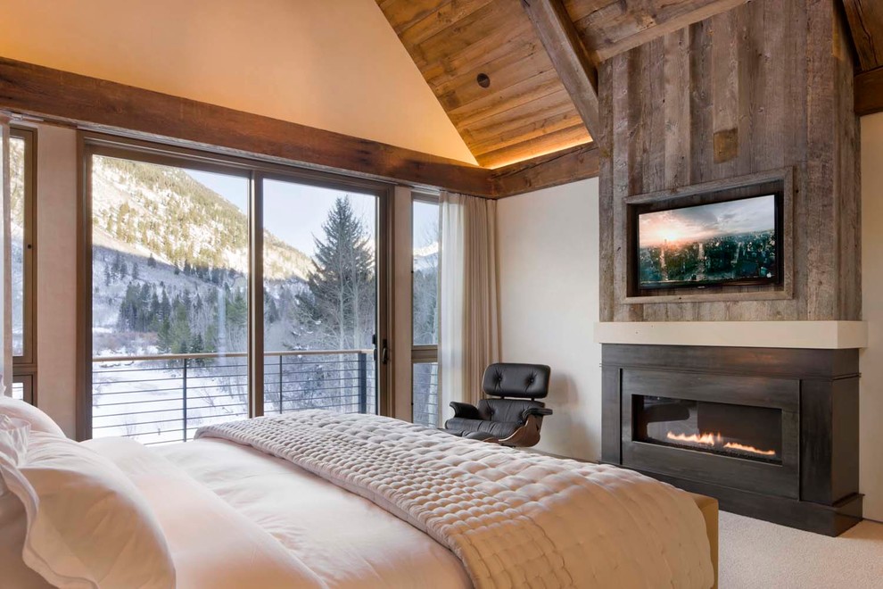 Design ideas for a large rustic master bedroom in Denver with beige walls, carpet, a ribbon fireplace, a metal fireplace surround and beige floors.