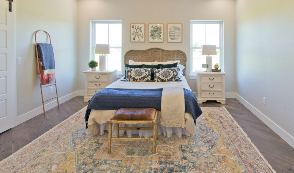This is an example of a farmhouse master bedroom with white walls, medium hardwood flooring and brown floors.