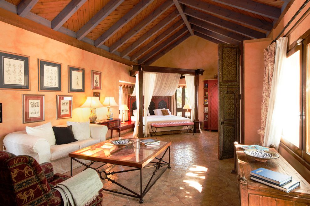 Expansive mediterranean master bedroom in London with terracotta flooring and orange walls.