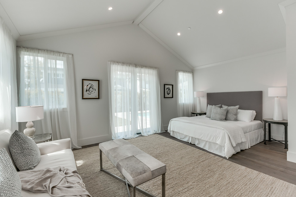Modelo de dormitorio principal actual grande con paredes blancas, suelo de madera en tonos medios y suelo marrón