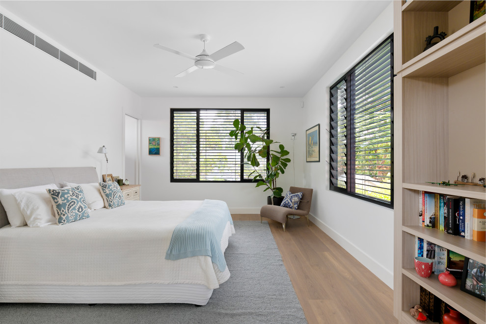Photo of a modern bedroom in Sydney with white walls, medium hardwood flooring and brown floors.