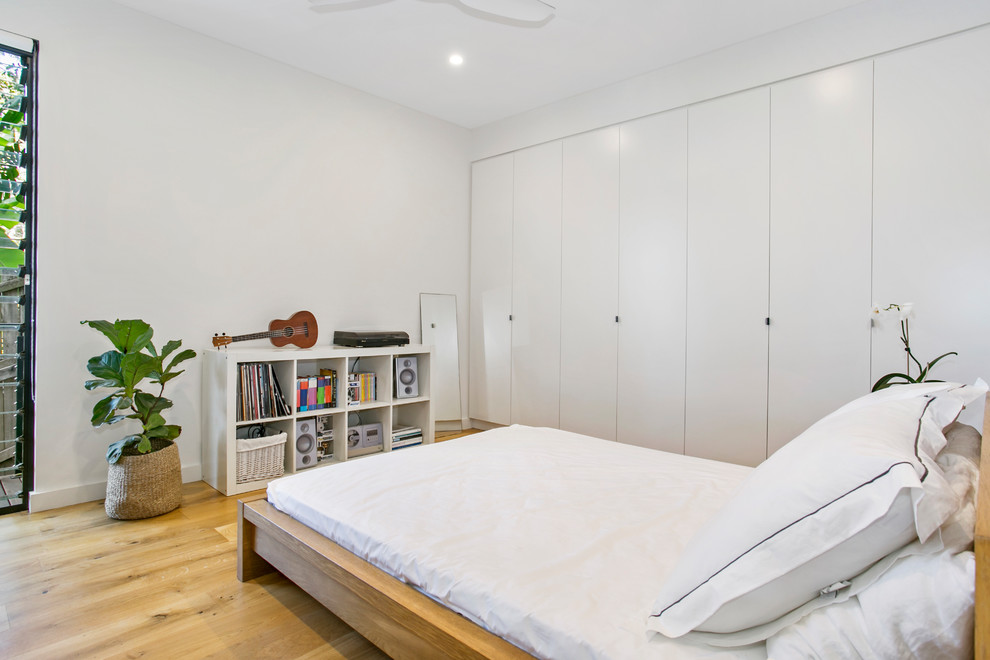 Exemple d'une chambre d'amis tendance avec un mur blanc, parquet clair et un sol beige.