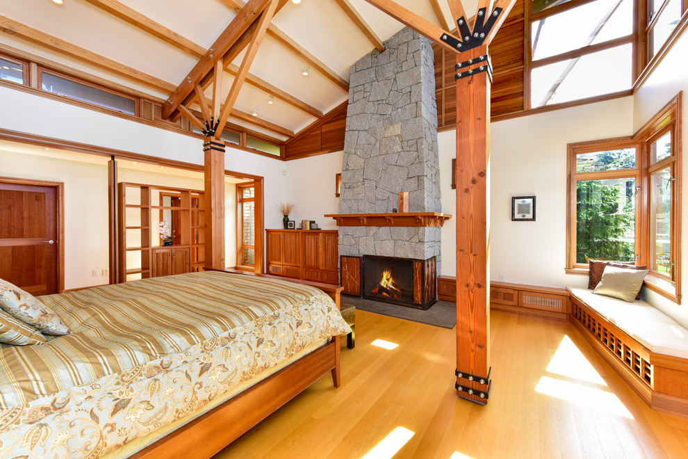 Maritimes Schlafzimmer mit weißer Wandfarbe, braunem Holzboden, Kamin und Kaminumrandung aus Stein in Seattle
