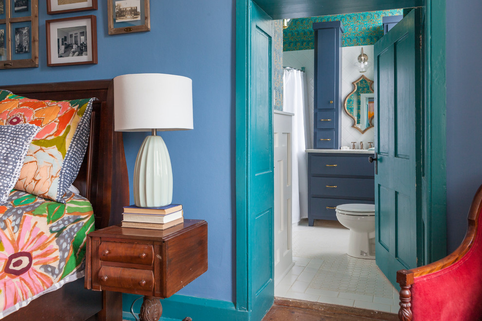 Cette photo montre une chambre parentale éclectique de taille moyenne avec un mur bleu, un sol en bois brun et un sol marron.