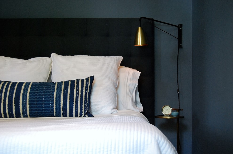 Modelo de dormitorio principal pequeño sin chimenea con paredes azules y suelo de madera en tonos medios