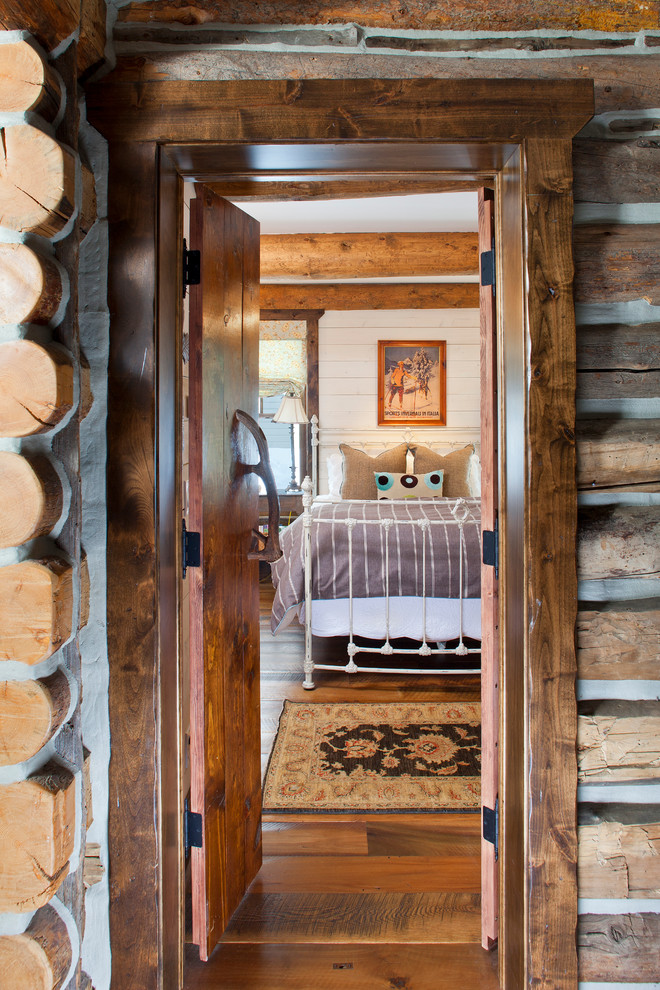 Immagine di una piccola camera degli ospiti rustica con pareti bianche e pavimento in legno massello medio