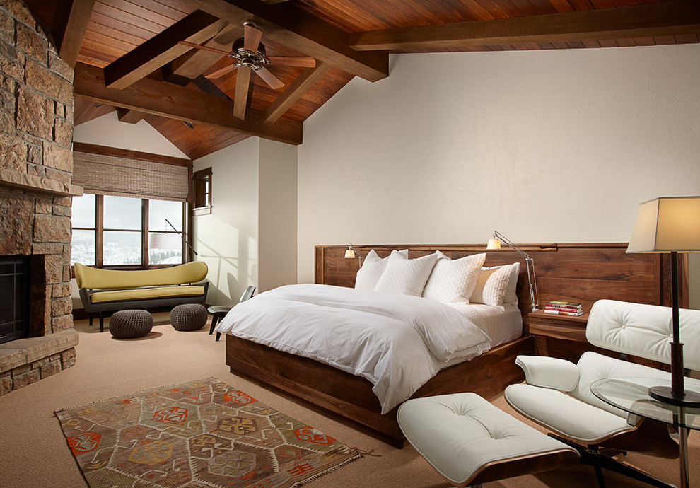 Réalisation d'une chambre avec moquette chalet avec un mur beige et un manteau de cheminée en pierre.