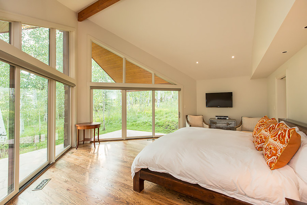 Modelo de dormitorio principal contemporáneo de tamaño medio con paredes blancas y suelo de madera clara