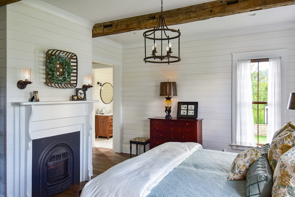 Cette photo montre une chambre parentale nature avec un mur blanc, parquet foncé, une cheminée standard, un manteau de cheminée en bois et un sol marron.