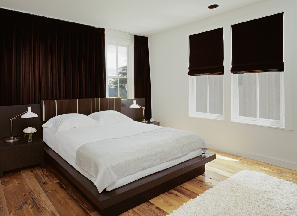 Cette photo montre une chambre chic avec un mur blanc, un sol en bois brun et aucune cheminée.