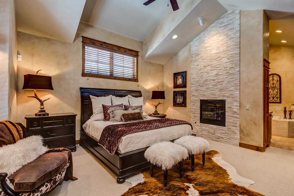 На фото: большая хозяйская спальня в стиле неоклассика (современная классика) с ковровым покрытием, стандартным камином и фасадом камина из камня