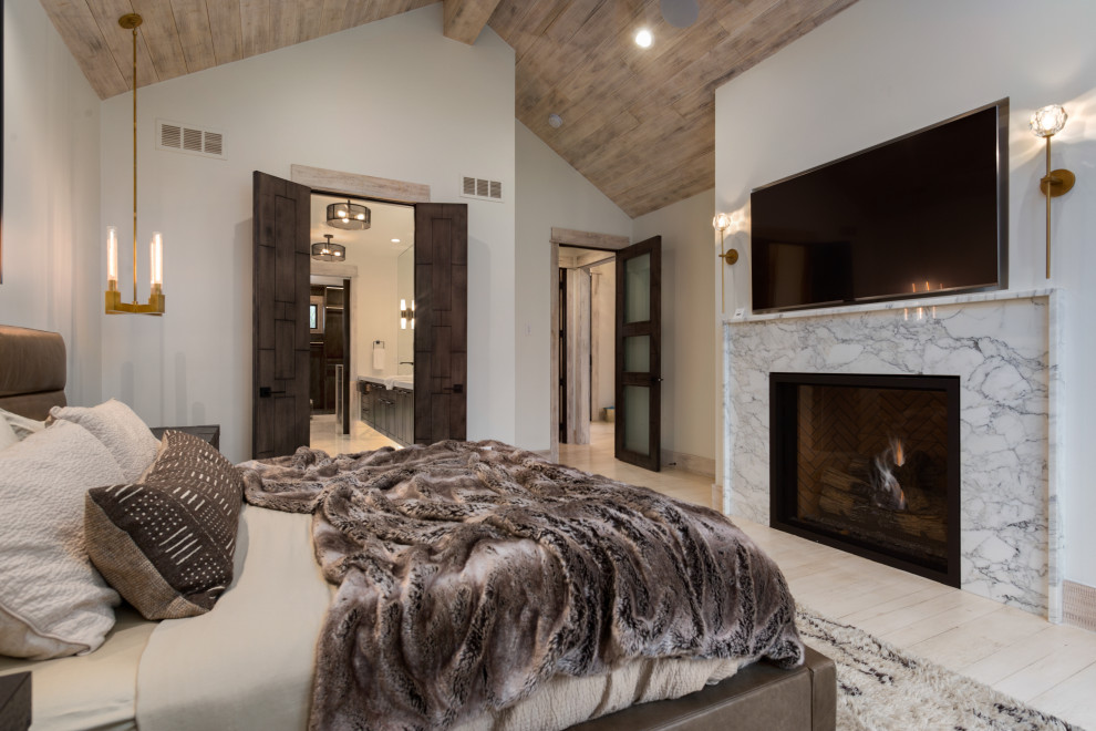 На фото: хозяйская спальня в стиле модернизм с белыми стенами, деревянным полом, стандартным камином, фасадом камина из камня и белым полом с