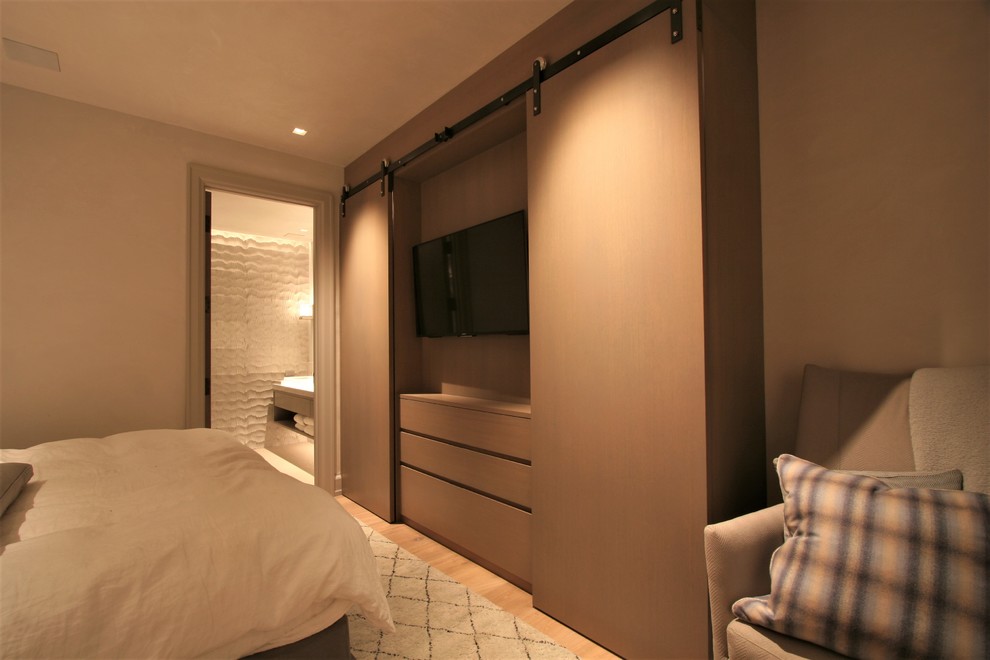 Imagen de dormitorio principal moderno de tamaño medio sin chimenea con paredes beige y suelo de madera clara